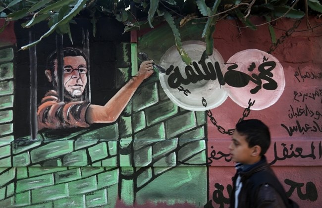 A Palestinian boy walks past a mural depicting Palestinian journalist Mohammed al-Qiq, during a demonstration on Feb. 1, 2016, in Gaza city. / AFP / MOHAMMED ABED