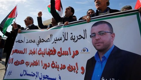Palestinians take part in a demonstration to demand the release of the Palestinian journalist | Photo: AFP