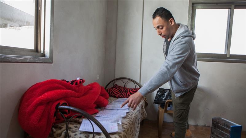 Nour Alyan, 27, who says he was held in stress positions for hours while in Israeli detention, displays the paperwork from his five separate arrests [Edmee Van Rijn/Al Jazeera]