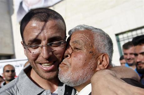 Palestinian journalist Mohammed al-Qeq, left is received by a relative on his arrival at the West... 