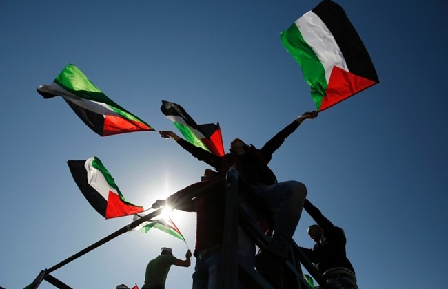  Palestinians hold national flags during a march on Feb. 19, 2016 in the West Bank village of Bilin, near Ramallah. / AFP / ABBAS MOMANI