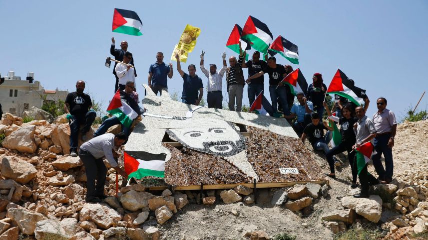 Palestinian activists stand around a mosaic portrait of Marwan Barghouti near an Israeli military installation in the West Bank city of Ramallah, May 9, 2017. Nasser Shiyoukhi/AP 