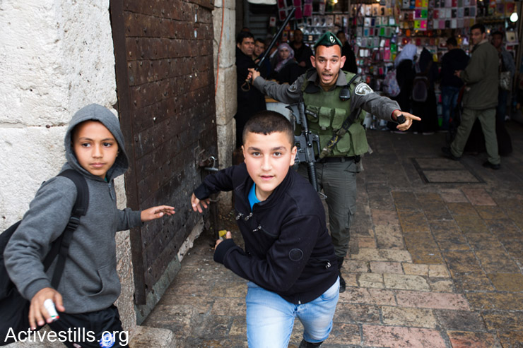 Israeli border police officer chases Palestinian children during land day demonstration in Damascus gate, East Jerusalem, March 30, 2014.