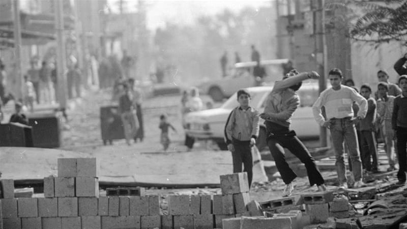 A youth throws stones in the direction of Israeli soldiers at the entrance to Bureij refugee camp in the occupied Gaza strip during the first intifada in 1987 [AP]