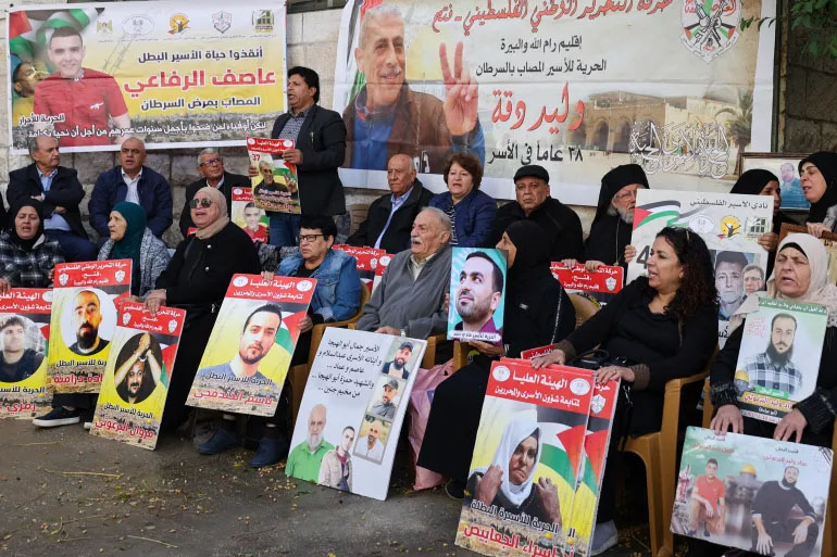 This image from November 21 shows relatives and supporters of Palestinians held in Israeli prisons staging a sit-in outside the Red Cross in Ramallah in the West Bank [Jaafar Ashtiyeh/AFP]